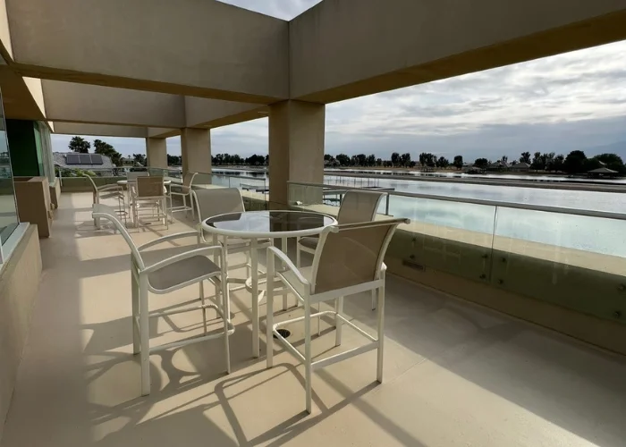Covered balcony terrace with patio table and chairs, glass balustrade and an ocean view